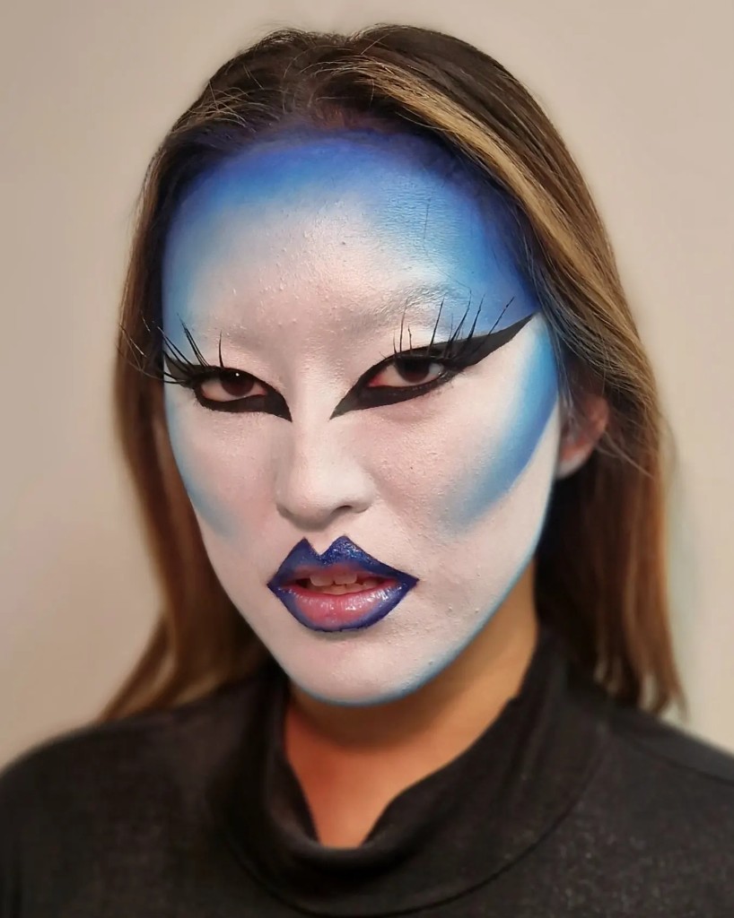 Blue and white graphic face paint with a sharp liner