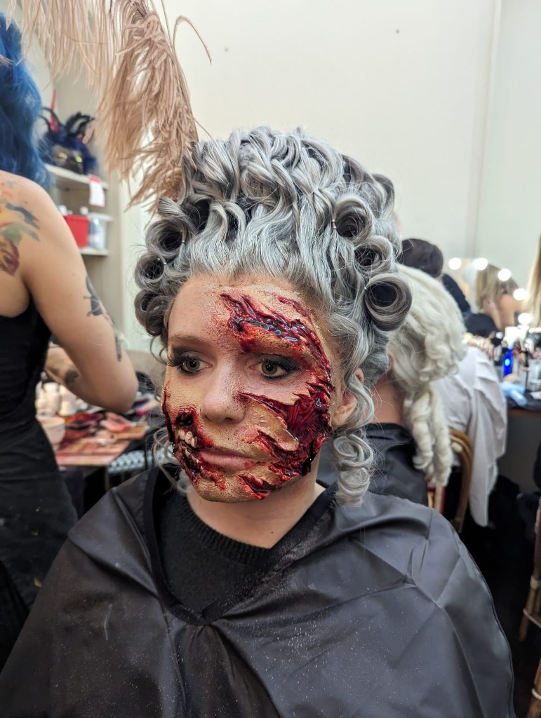Period curls and a facial prosthetic in the dressing room